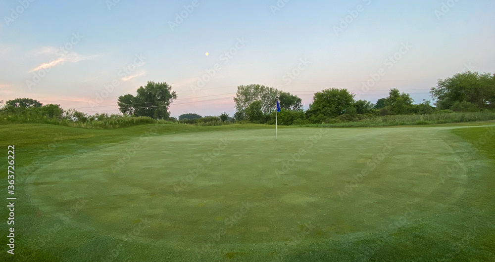 sunrise on golf course golf green flag pole sand trap morning moon