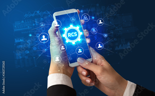 Female hand holding smartphone with RCS abbreviation, modern technology concept photo