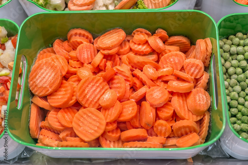 Frozen vegetables, fruits and berries. Food products are poured into rectangular plastic trays.