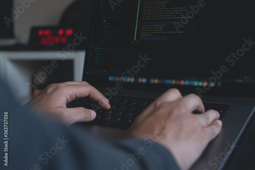 Programmer or software developer coding on laptop computer