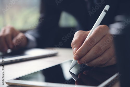 Businessman with stylus pen signing in on digital document or business contract while working in office