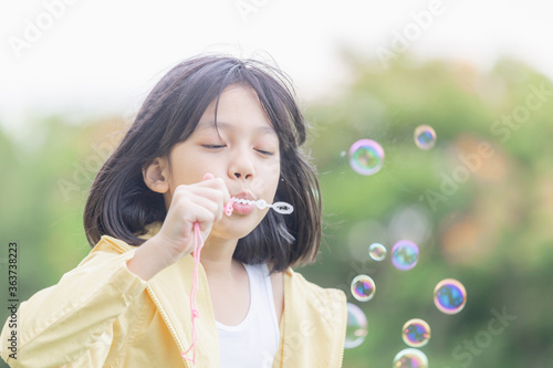 Cheerful a little girl blowing soap bubbles in the park  Kids playing concept