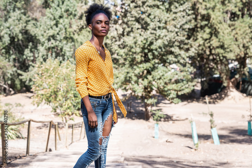 portrait young black woman in yellow shirt in the middle of nature in a park photo