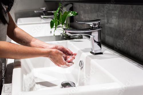 Young asian women washing hand with soap in faucet. New normal, coronavirus prevention.