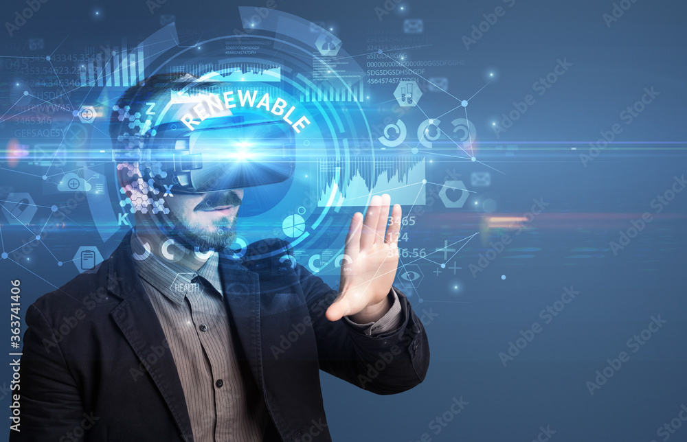 Businessman looking through Virtual Reality glasses with RENEWABLE inscription, innovative technology concept Businessman looking through Virtual Reality glasses with RENEWABLE inscription, innovative technology concept