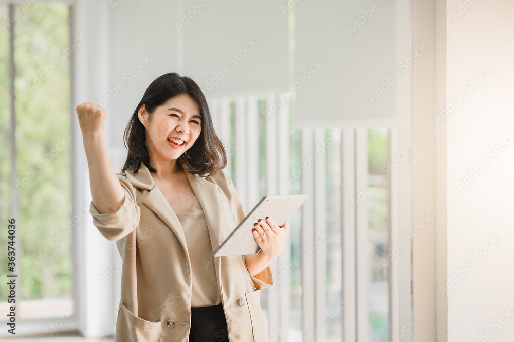 Asian woman holding digital tablet and raising her arm up