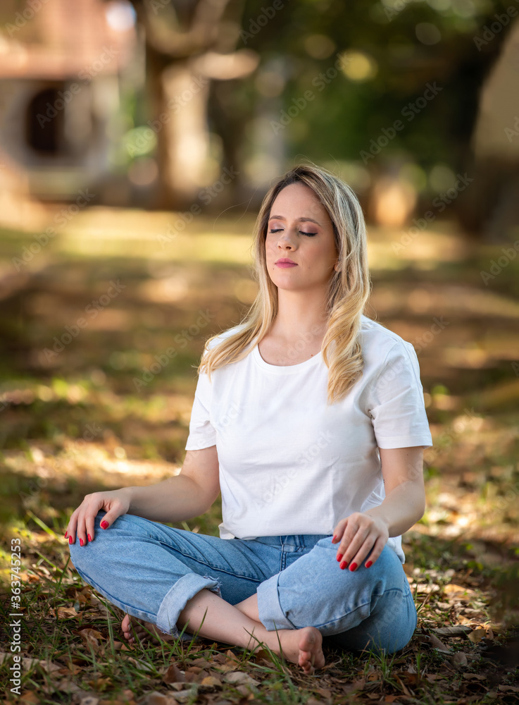 beautiful young woman meditating in park outdoors and under trees. beautiful young woman meditating in park outdoors and under trees.