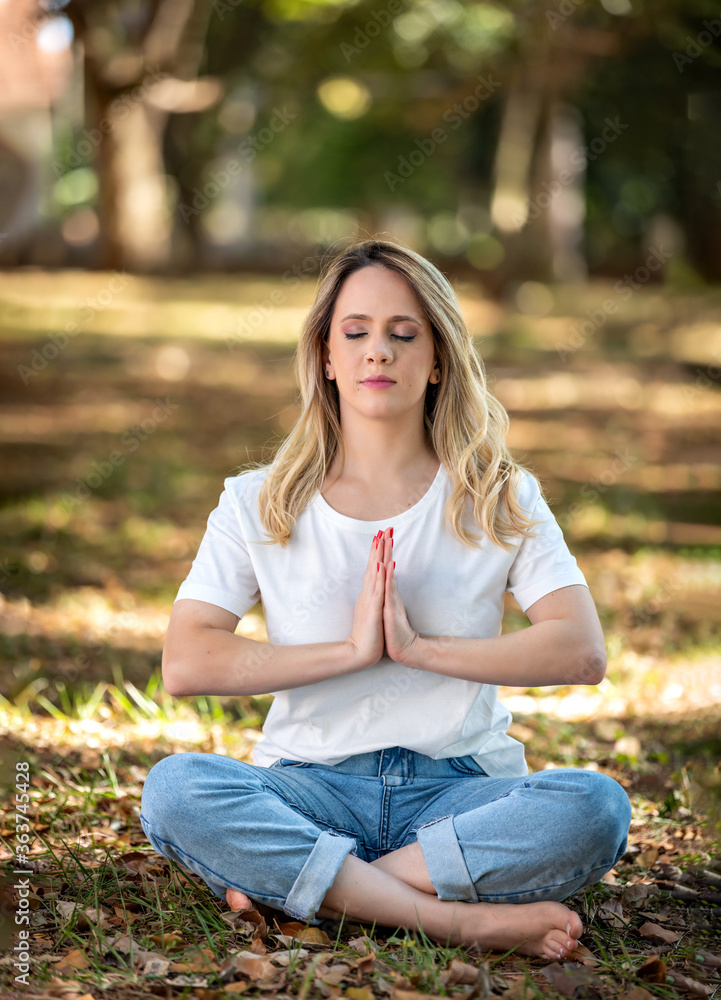 beautiful young woman meditating in park outdoors and under trees. beautiful young woman meditating in park outdoors and under trees.