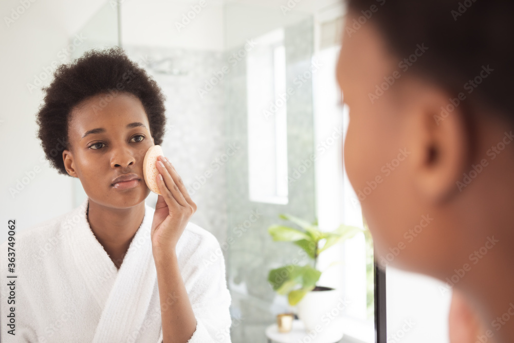 Woman applying makeup to her face while looking in the mirror Woman applying makeup to her face while looking in the mirror