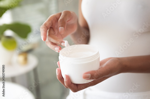 Mid section of woman using moisturizer