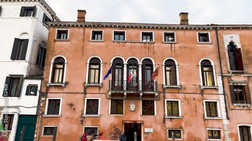 Front Facade Of Venetian Building And Museum Viewed From A Cruising Waterboat In Venice, Italy - low angle trucking shot photo