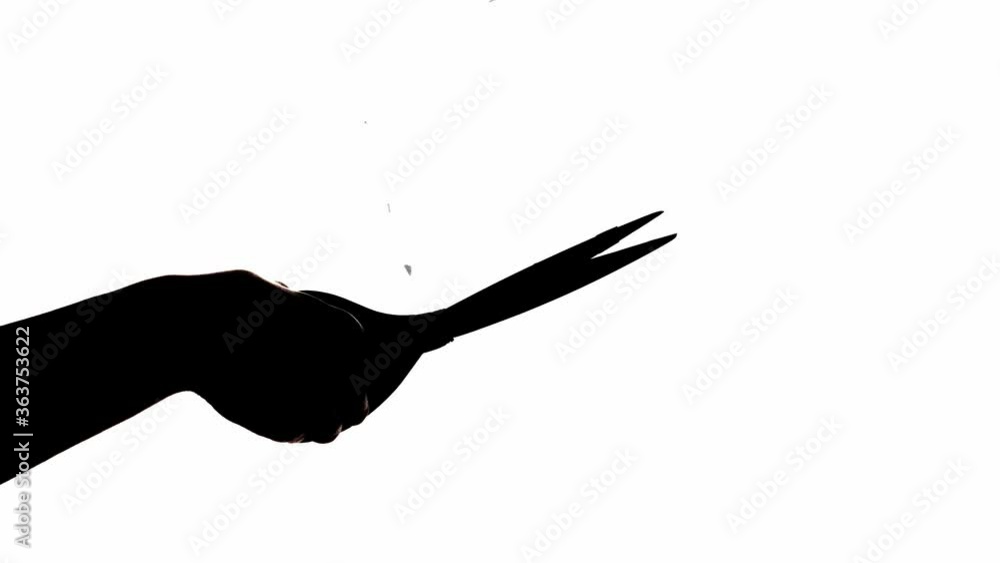 Silhouette of male hand with scissors and falling paper pieces on white background Silhouette of male hand with scissors and falling paper pieces on white background