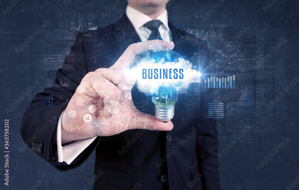 Businessman holding a light bulb with BUSINESS inscription, new business concept Businessman holding a light bulb with BUSINESS inscription, new business concept