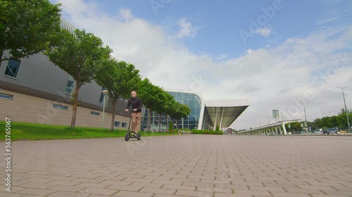 Successful young man rides an electric scooter near the business center. Young people on an electric scooter.