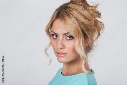 Closeup portrait of a young beautiful woman in a light blue dress in the studio © kanzefar