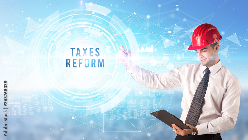 Handsome businessman with helmet drawing TAXES REFORM inscription, contruction business concept Handsome businessman with helmet drawing TAXES REFORM inscription, contruction business concept