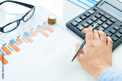 Finance and business concept. Female small business. Hand with calculator coins on financial graphs on desk and glasses coins. Accounting budgeting or market analysis. Home finance. copy space. loans