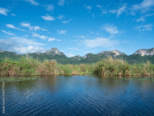 Rock cliff and green forest in lake with blue sky and white could in background, Reflection of Limestone mountain on water of the vast wetland at Khao Sam Roi Yot National Park , Thailand © anant_kaset