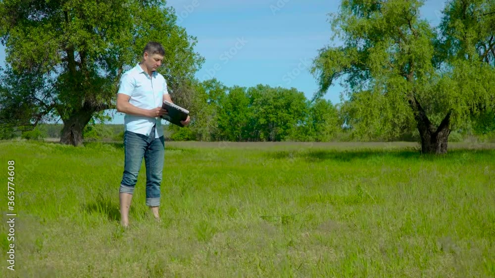 Man Works behind a Laptop on the lawn. At The Sunny Day. Freelancer Remote Work Concept. 4K Man Works behind a Laptop on the lawn. At The Sunny Day. Freelancer Remote Work Concept. 4K