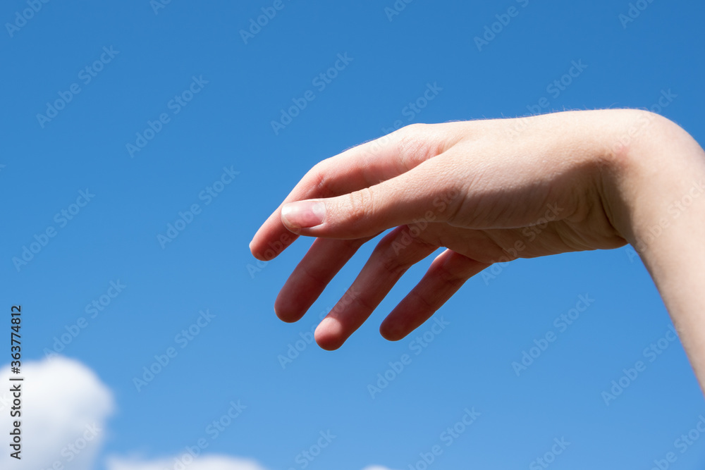 Empty open female hand, relaxed gesture on a background of blue sky. Can be used as a basis for design, copy space Empty open female hand, relaxed gesture on a background of blue sky. Can be used as a basis for design, copy space