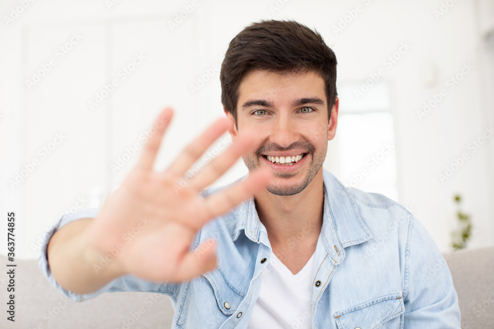 Portrait happy smiling young man waving hand, looking at camera, greeting, saying hello, head shot portrait. Portrait happy smiling young man waving hand, looking at camera, greeting, saying hello, head shot portrait.