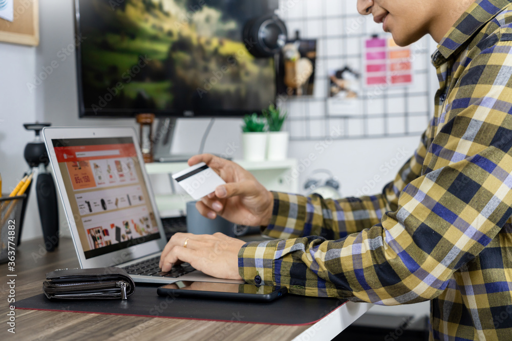 Asian man holding credit card to Online shopping with laptop computer and entering security code
Asian man holding credit card to Online shopping with laptop computer and entering security code