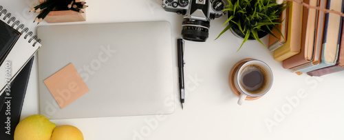 Modern workspace with laptop, stationery, camera, books and decorations on white table