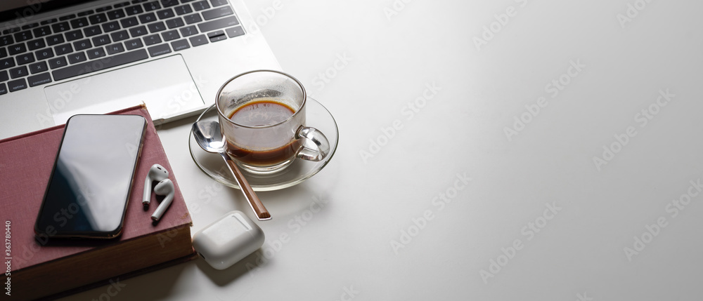 Simple workspace with copy space, laptop, coffee cup, book, smartphone and wireless earphone Simple workspace with copy space, laptop, coffee cup, book, smartphone and wireless earphone