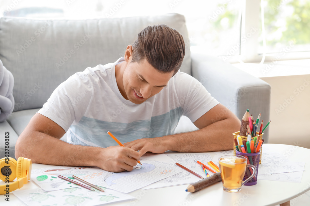 Young man coloring pictures at home Young man coloring pictures at home