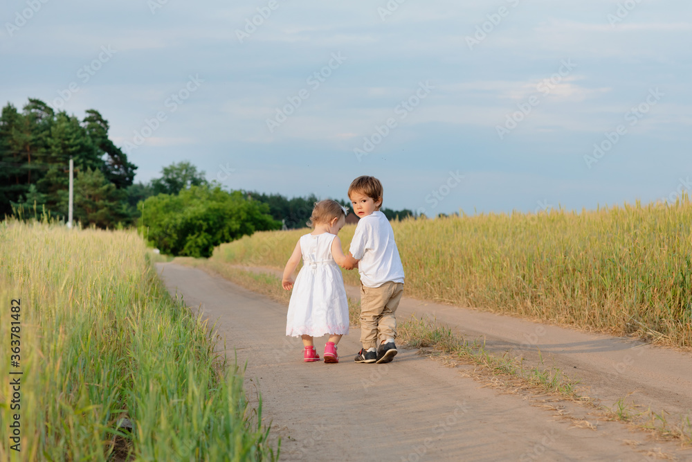 The little boy is carefully holding the little girl's hand they are looking into the distance The little boy is carefully holding the little girl's hand they are looking into the distance