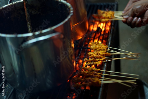 Food Vendor Grilling Meat Satay with charcoal at Street Food Market