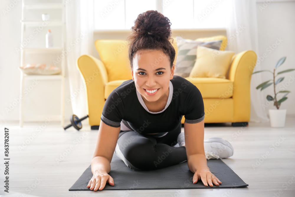 Fototapeta premium Sporty young woman training at home