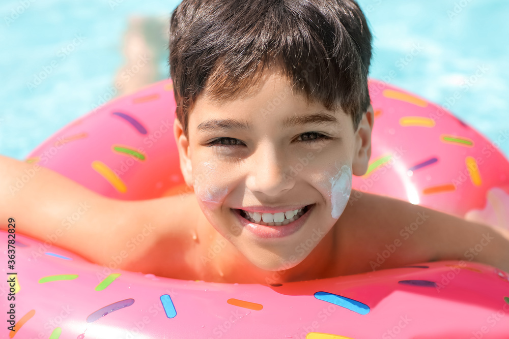 Little boy with sun protection cream on his face and inflatable ring in swimming pool Little boy with sun protection cream on his face and inflatable ring in swimming pool