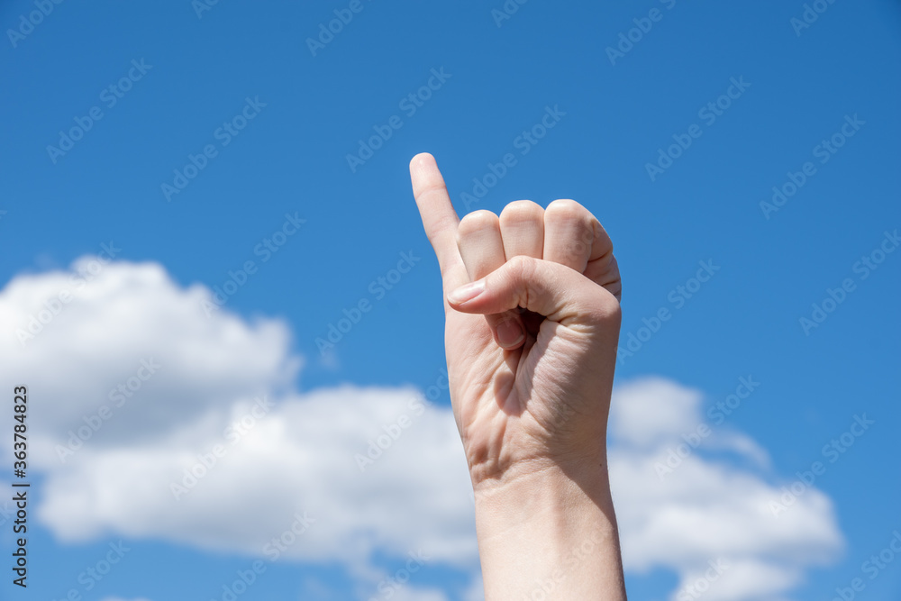 Hand clenched into a fist with an extended little finger on a blue background, concept of promising hand, reconciliation Hand clenched into a fist with an extended little finger on a blue background, concept of promising hand, reconciliation