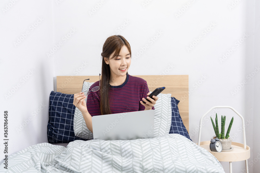 Asian woman working with smartphone or laptop in bedroom at her home
Asian woman working with smartphone or laptop in bedroom at her home