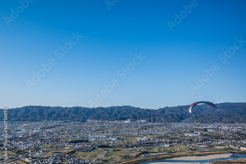 青空に向かって飛ぶパラグライダー