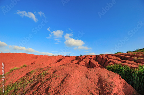 The red land is under the blue sky and white clouds.