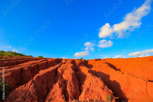The red land is under the blue sky and white clouds.