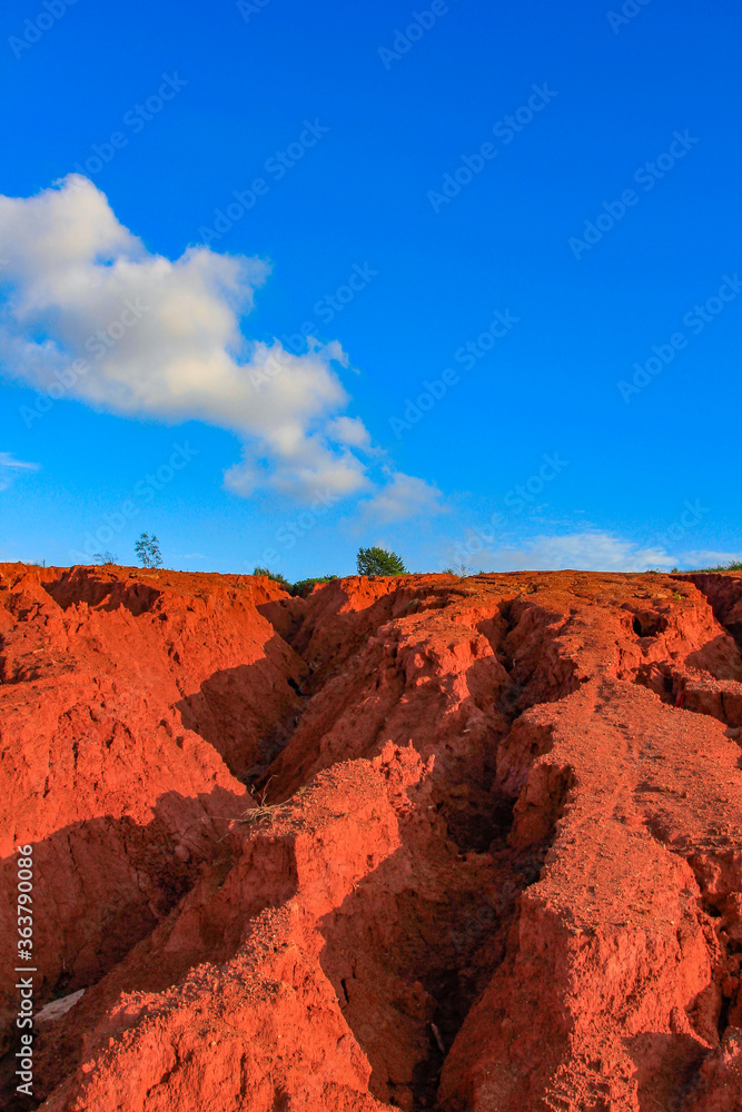 Fototapeta premium The red land is under the blue sky and white clouds.