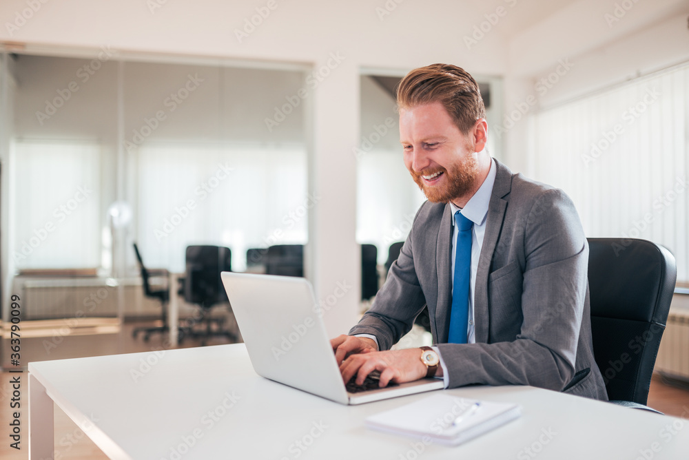 Happy businessman in formalwear typing on laptop in the office. Happy businessman in formalwear typing on laptop in the office.