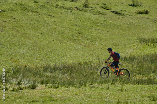 a man on a mountain bike going through a green field