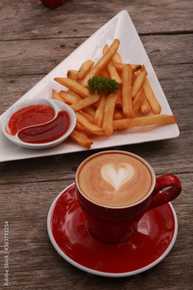 a cup of coffee and french fries on a wooden table. a cup of coffee and french fries on a wooden table.