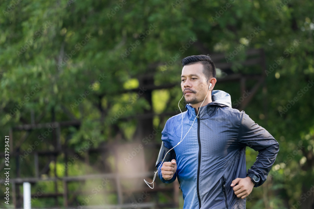 A man in sport hoodie jogging in the city park in the evening after stressful work. Runner jogging training and workout exercising power walking outdoors in forest city. Stock photo A man in sport hoodie jogging in the city park in the evening after stressful work. Runner jogging training and workout exercising power walking outdoors in forest city. Stock photo