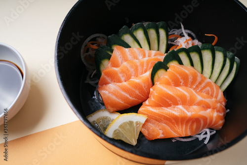 Slice salmon raw sashimi serve on ice with fresh cucumber and lemon.