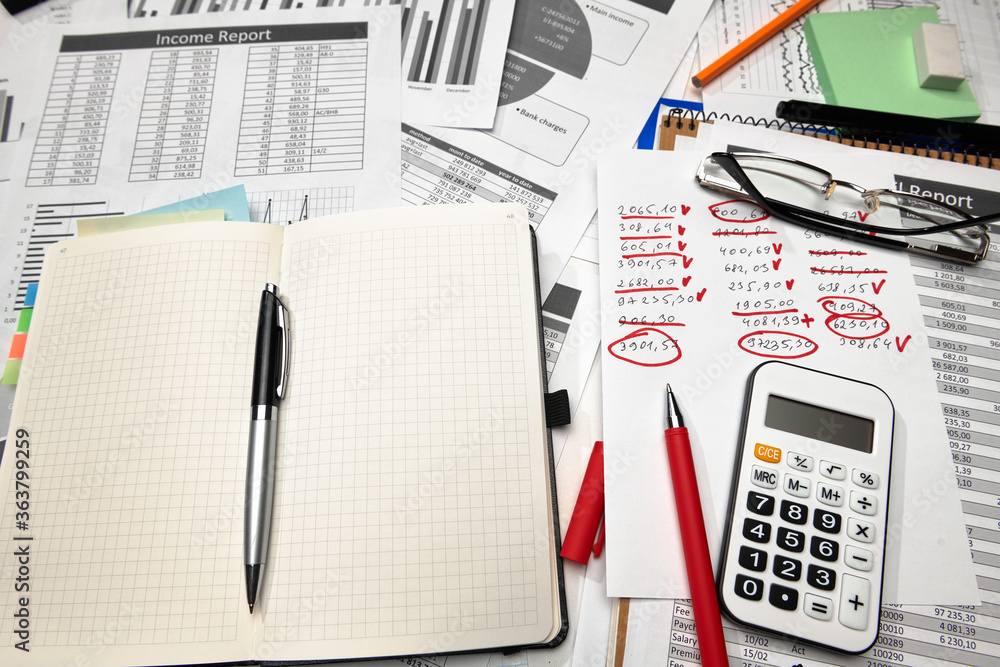 Top view of office employee's desk - work with financial reports, analysis and accounting, tables and graphs, various office items for bookkeeping Top view of office employee's desk - work with financial reports, analysis and accounting, tables and graphs, various office items for bookkeeping