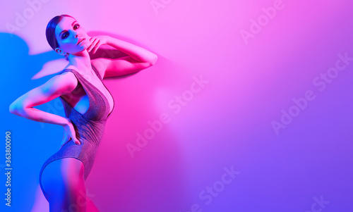 High Fashion. Woman in colorful neon light, make-up. Sexy girl, stylish hair, trendy bodysuit, makeup. Party disco neon style. Creative art beauty concept, fashionable fitness model, bright color