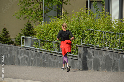 A woman is jogging alone in urban environment. Outdoor sports activities are recommended because of Covid-19 pandemic. Photographed in Espoo  Finland.