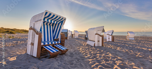Sunset at calm beach with beach chairs  photo