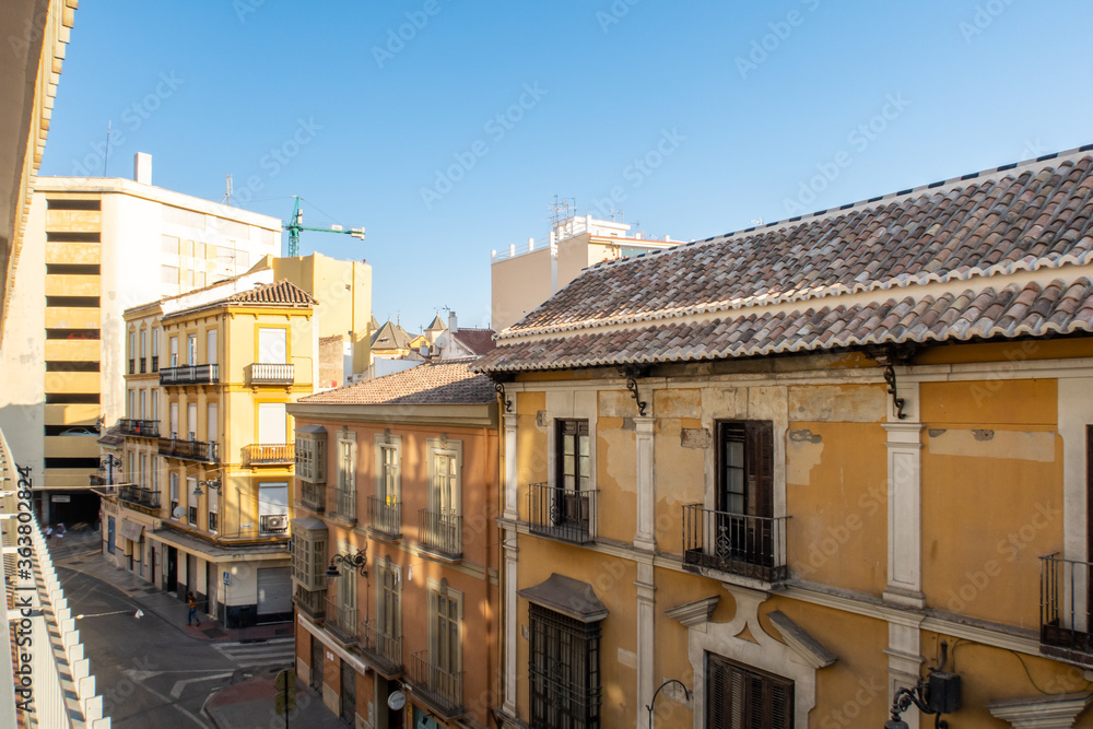 MALAGA, Spain. Calle Pena, old medieval narrow street in Malaga, Spain, with Spanish style buildings, windows and wooden roofs, colorful facades with crystal blue sky in the background.