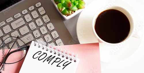 Office supplies, devices, coffee cup and glasses on white table with text COMPLY